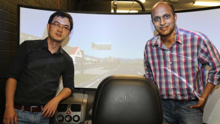 Dr Xhitao Xiong and Dr Vinayak Dixit in front of a car simulator at the University of New South Wales.